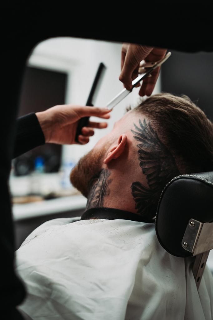 Detail of a straight-razor line-up beside a wing tattoo
